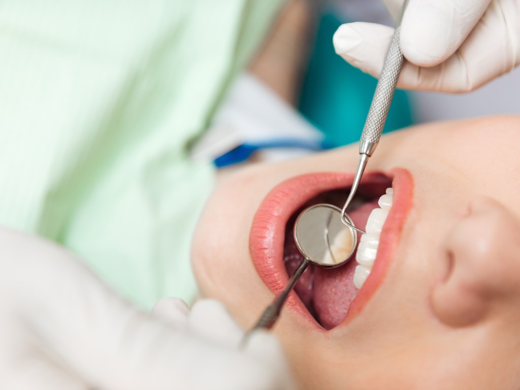 dentiste sondant une bouche de femme